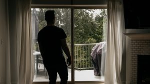 man looking out sliding glass doors