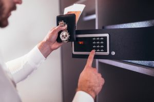 Men's hand opens a safe hidden in the wardrobe. Small home or hotel safe