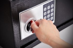 A woman's hand unlocking a safe with a digital lock.