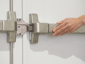 Person's hand pushing exit bar on commercial door